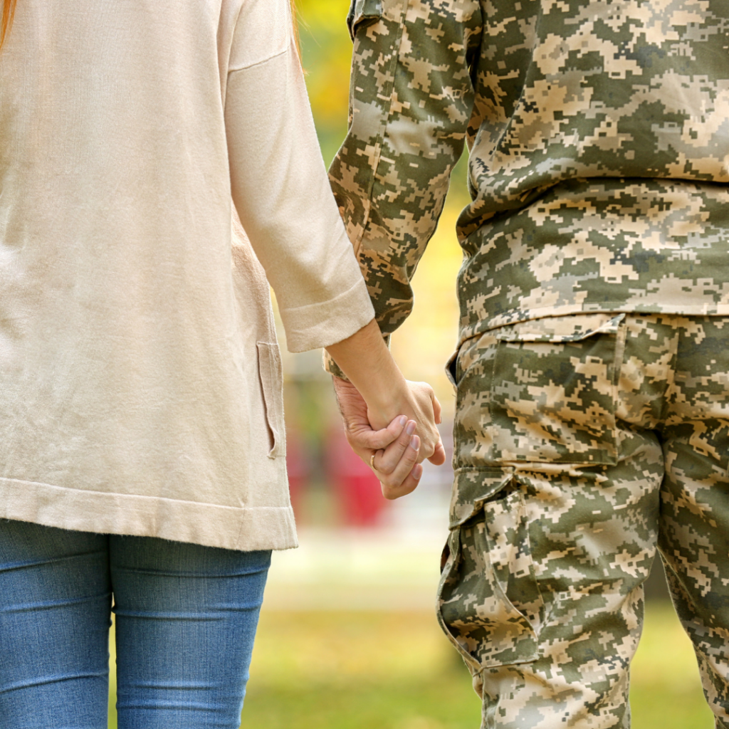 Eine Frau in ziviler Kleidung und ein Soldat in Uniform halten sich bei der Hand